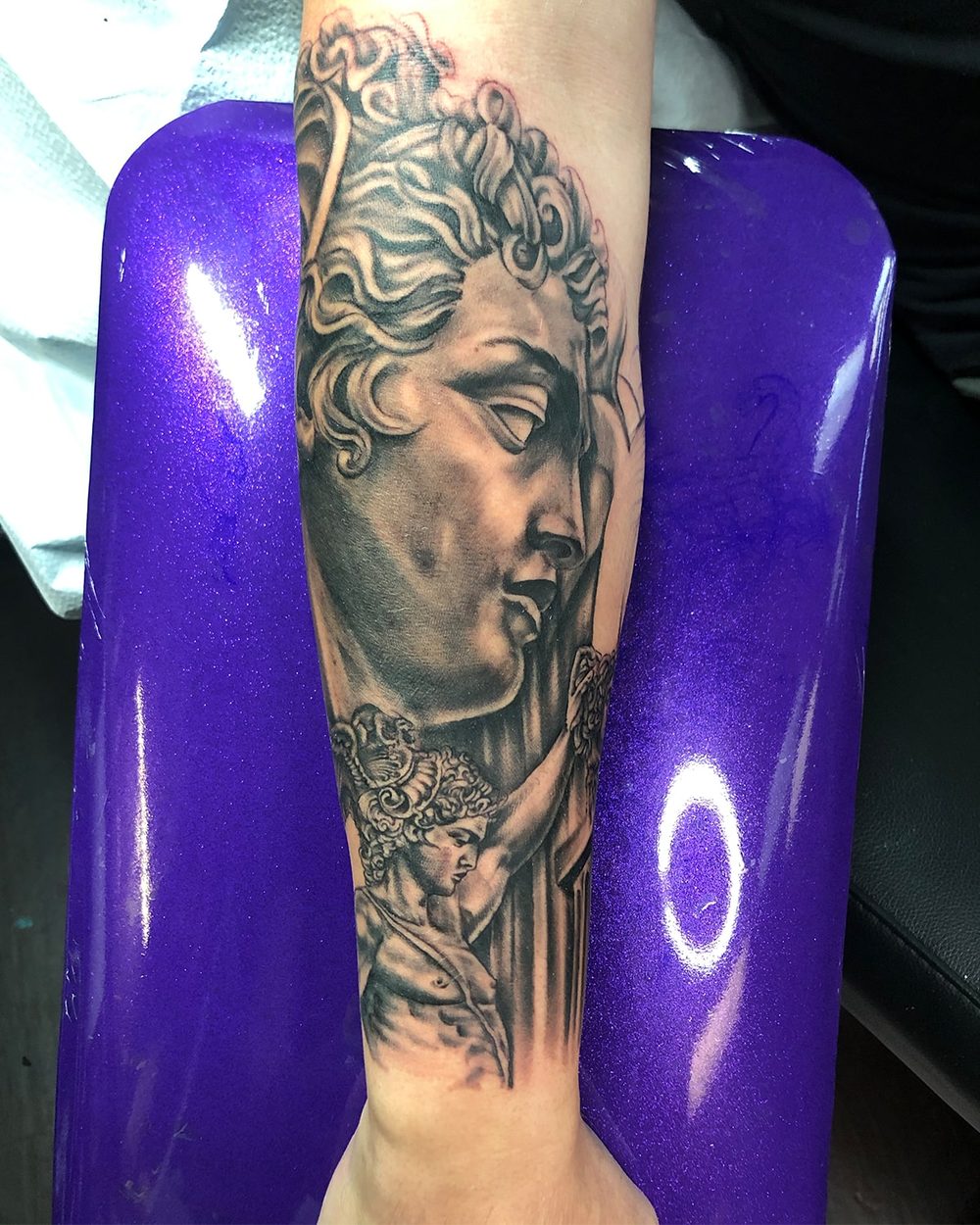 Black and grey classical statue portrait tattoo on a forearm by Jeremy Sramek