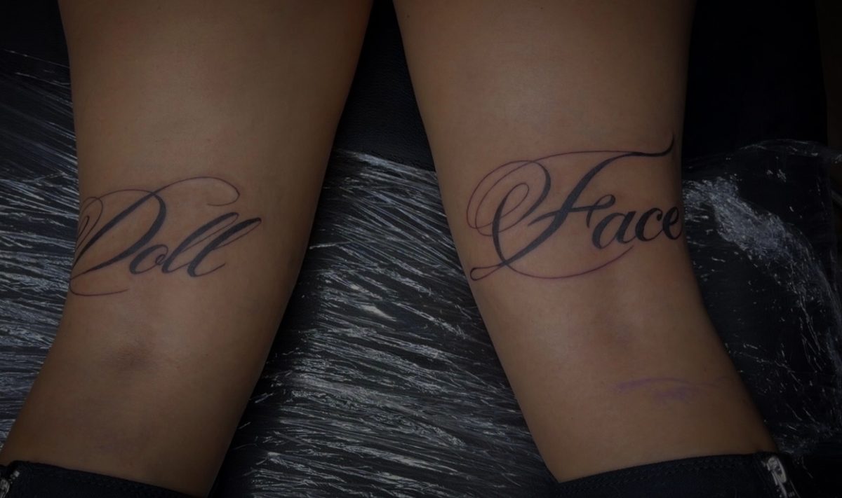 Doll Face script lettering tattoo behind the knees by Kain Sramek