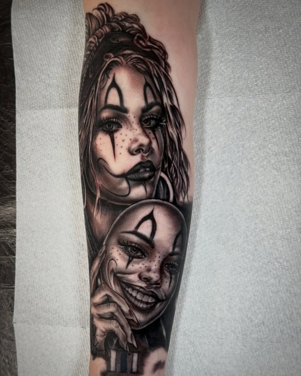 Healed black and grey tattoo of a woman in clown makeup holding a mask