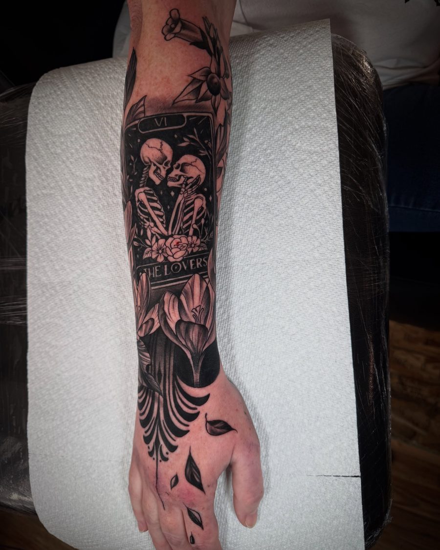 The Lovers tarot card with a skeleton couple, a black and grey forearm tattoo by Jeremy Sramek