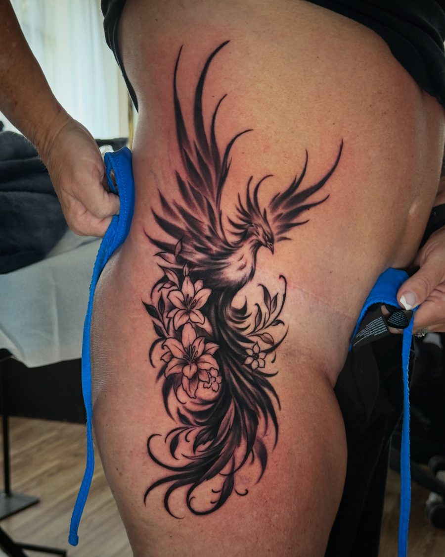 Phoenix and flowers, a blackwork hip tattoo by Jeremy Sramek