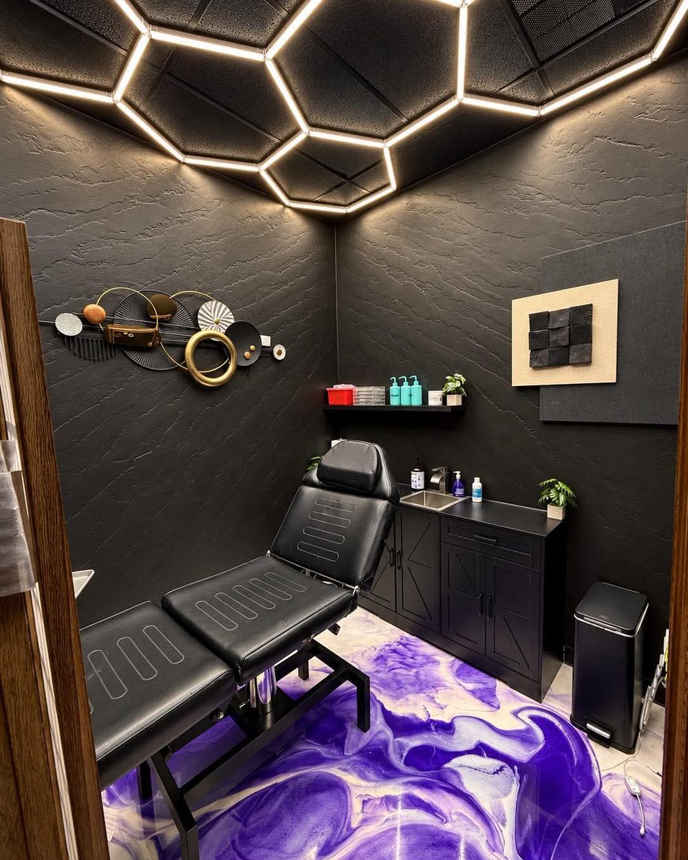 A private tattoo room at Vanity Ink set up for a session under a hexagon ceiling light