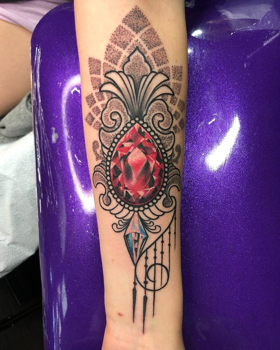 Red jewel with ornamental dotwork, a forearm tattoo by Jeremy Sramek