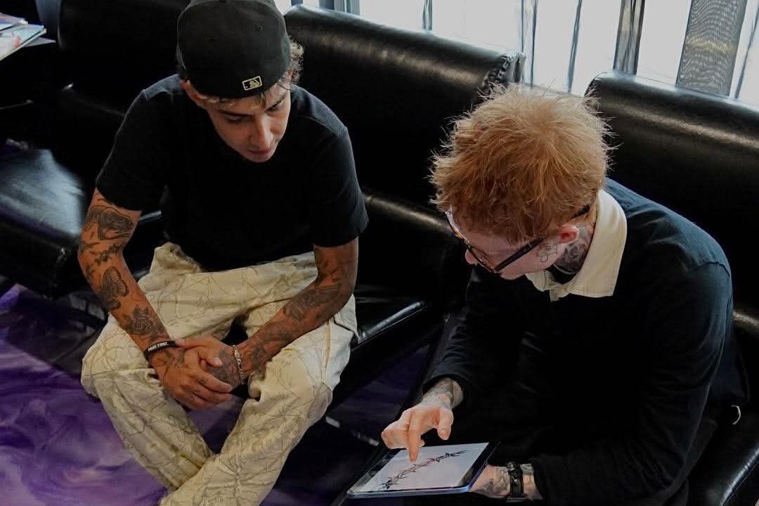 Kain Sramek going over a tattoo design on a tablet with a client at Vanity Ink in Wheat Ridge