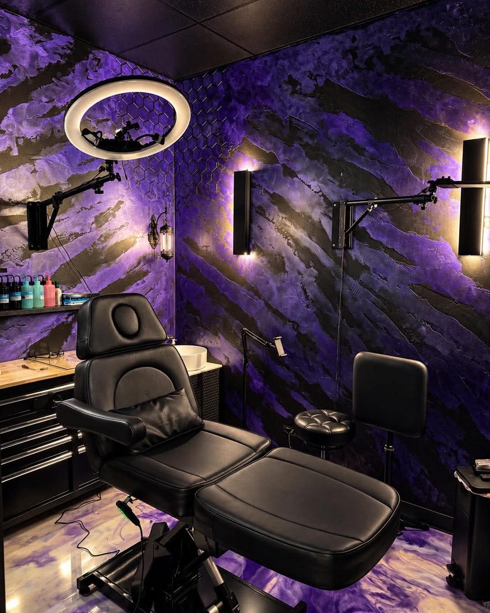 A tattoo workstation at Vanity Ink: the chair, a ring light and the purple and black wall